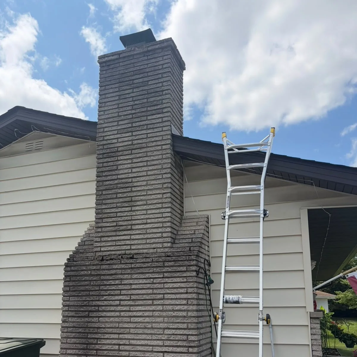Tall exterior chimney with weathered masonry before repair